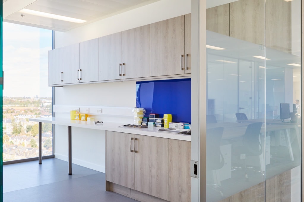 Redesigned healthcare workplace room with cupboard units and floor to ceiling glass window