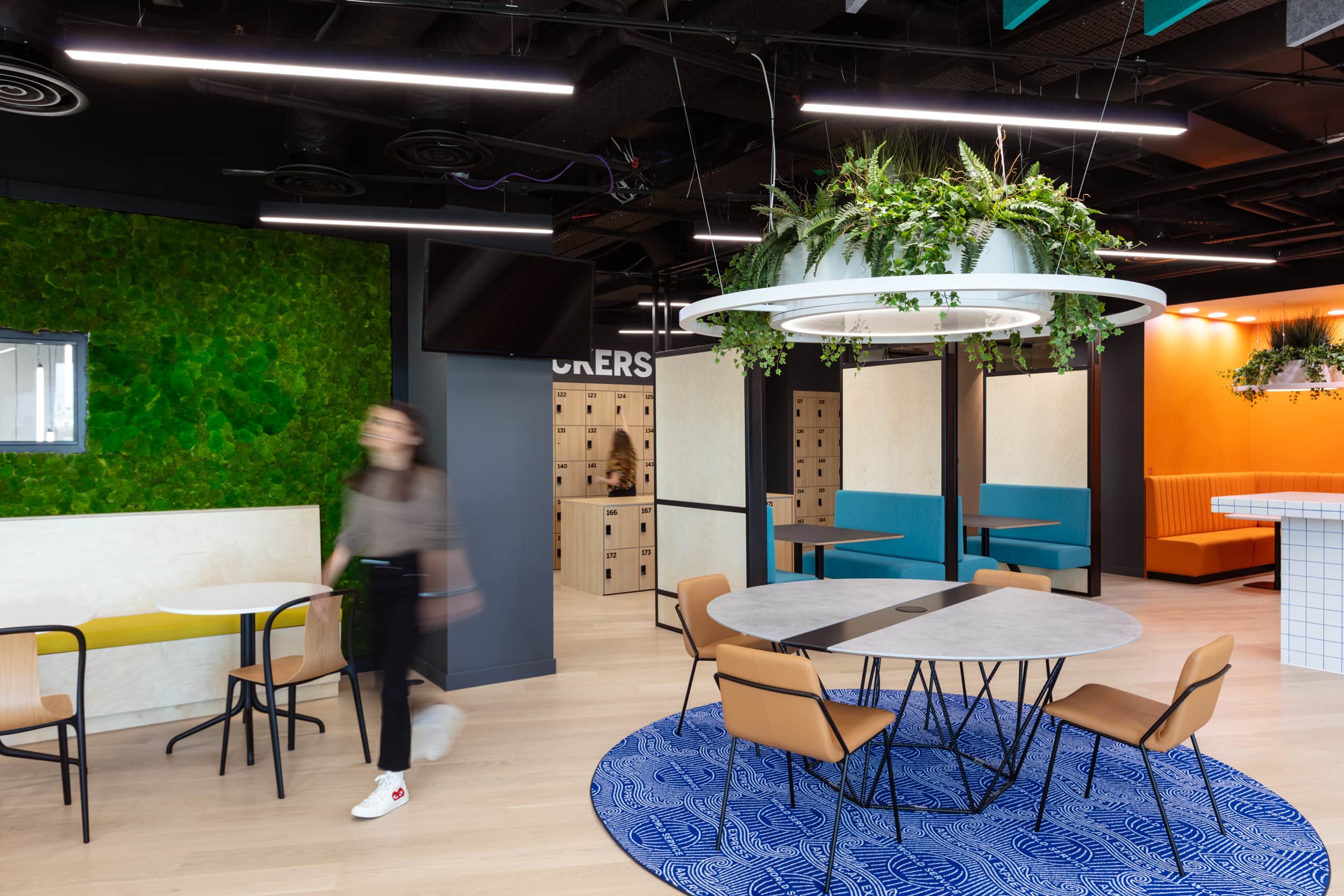 Inside the staff canteen area where a moss wall and a feature planter hang above a collection of dining chairs and tables.