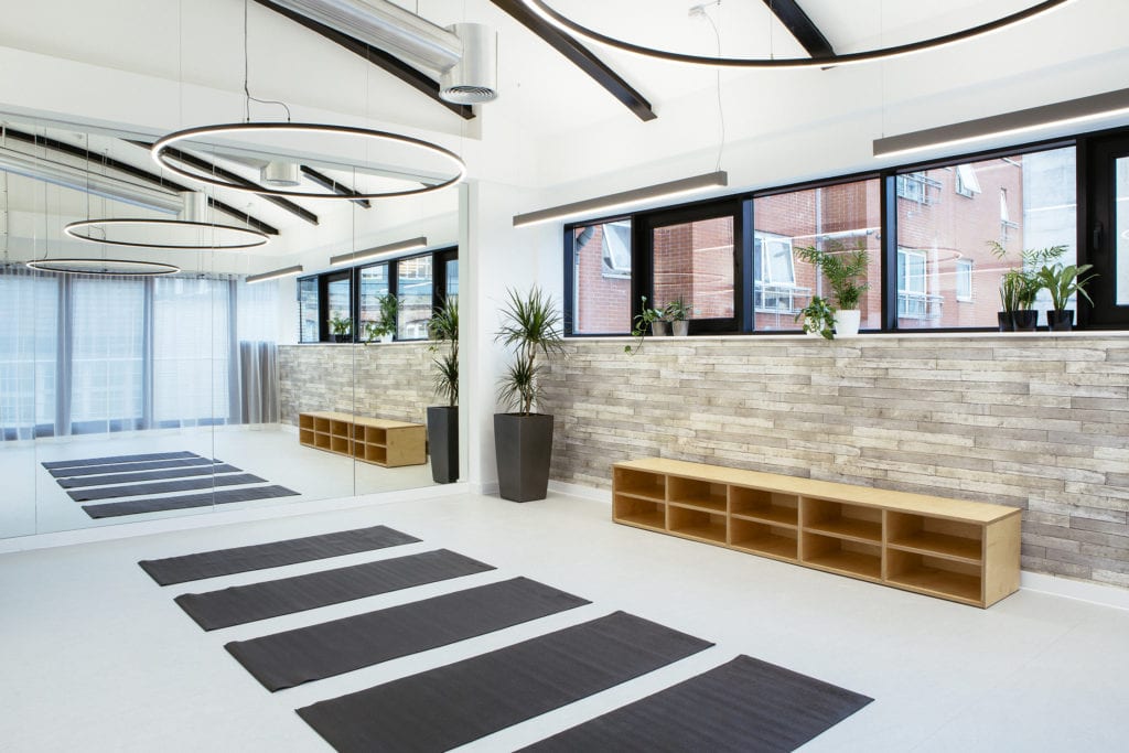 Yoga studio with yoga mats, plants and floor to ceiling mirrors.