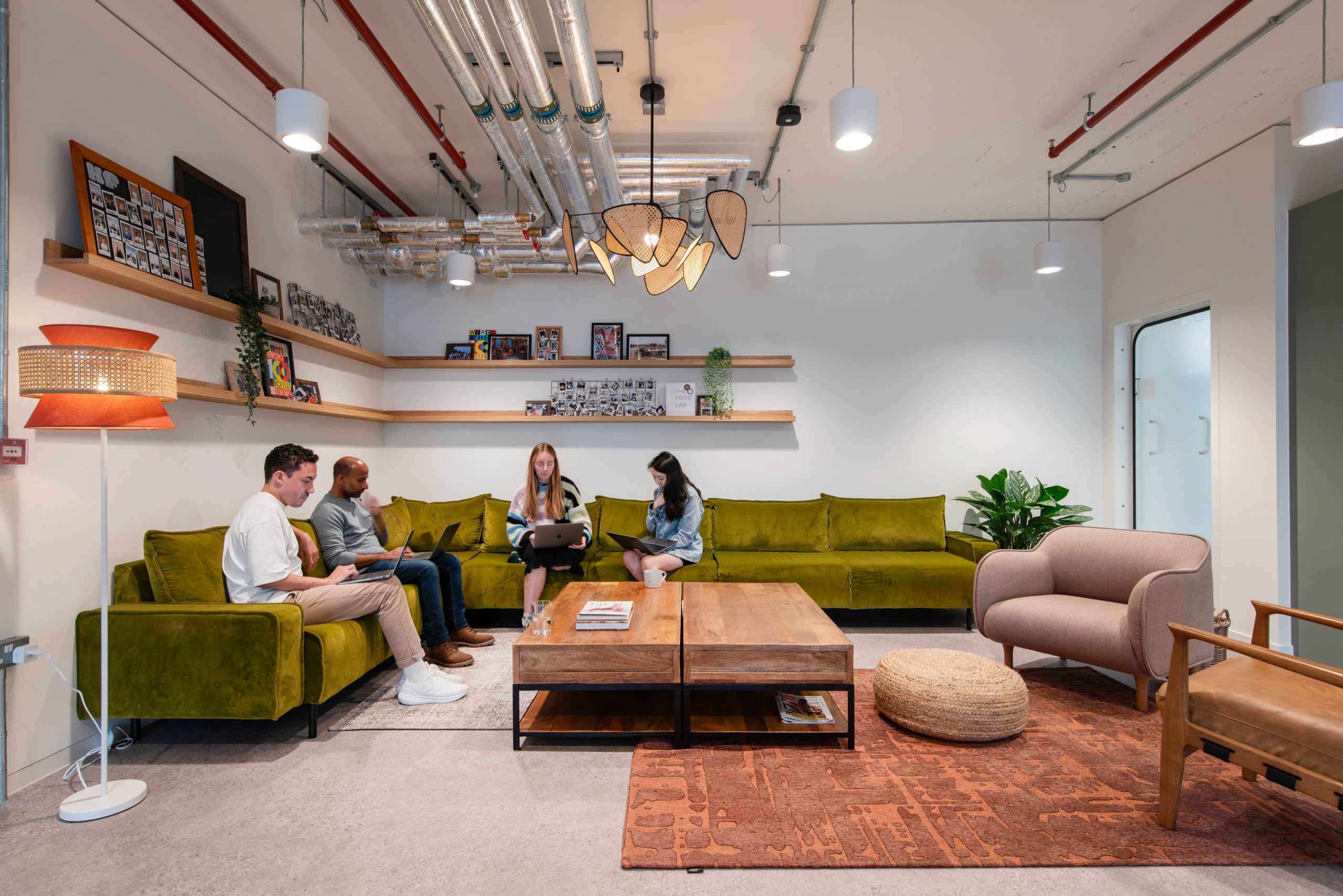 A group of people are shown working together in a comfortable lounge setting that helps enable all personality types to feel comfortable in the workplace.