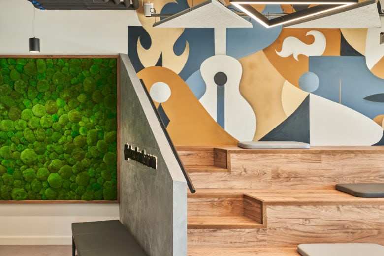 Workplace bleacher-style seating with graphic wall art and green wall.