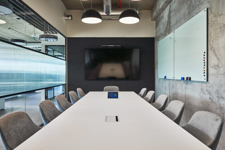 Workplace boardroom with large table and screen.