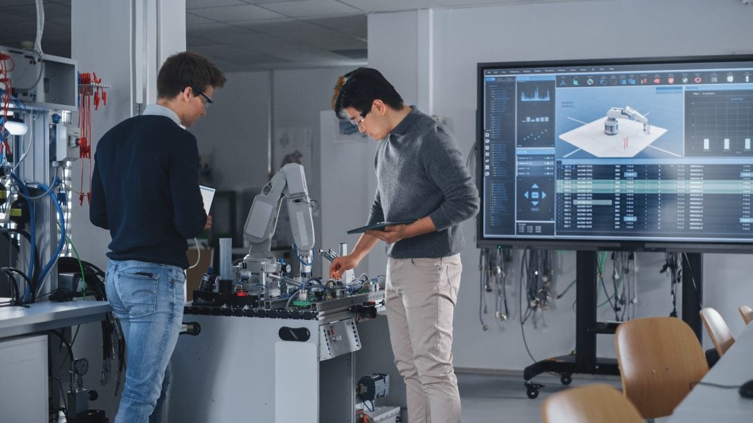 Two engineers working on robot arm design in a modern laboratory workspace. 