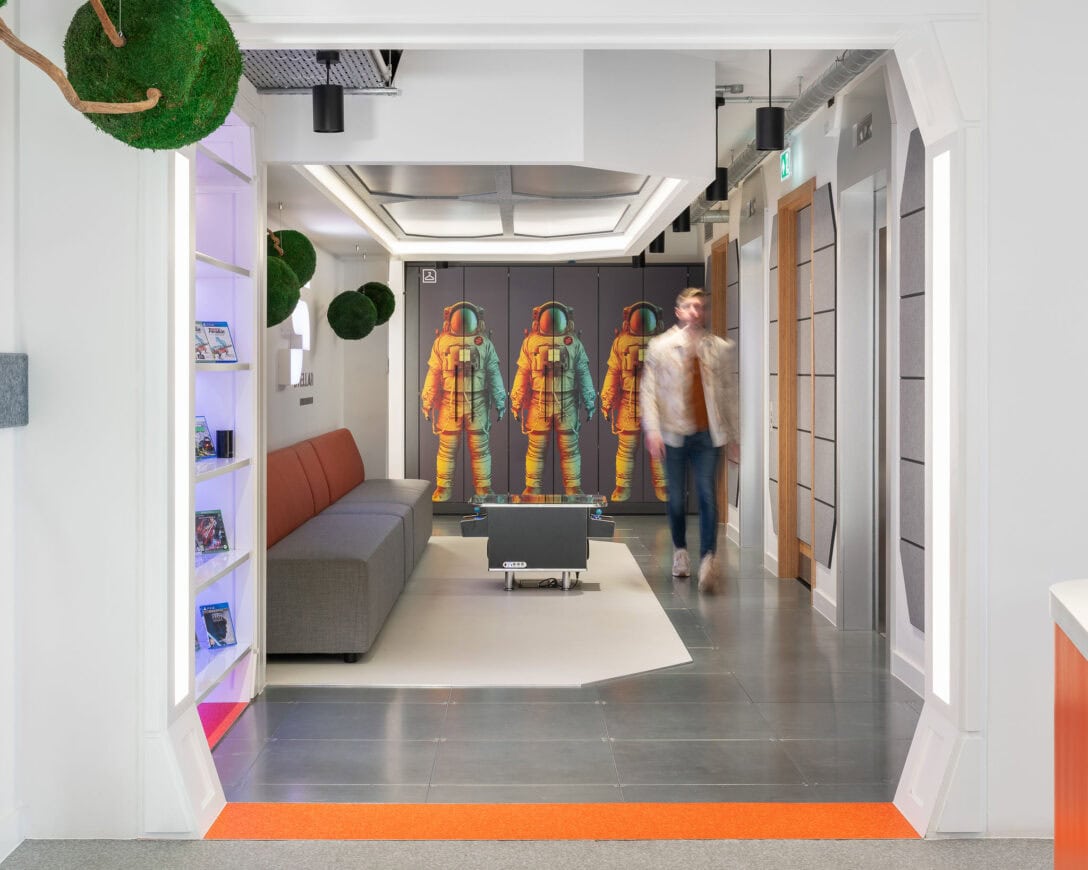 A man is shown walking down the office corridor of the Stellar Entertainment offices designed by AIS. The space looks like a spaceship inside.