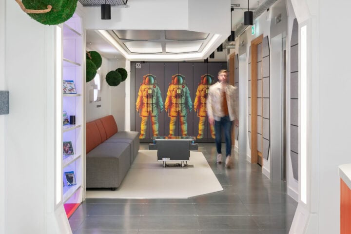 A man is shown walking down the office corridor of the Stellar Entertainment offices designed by AIS. The space looks like a spaceship inside.